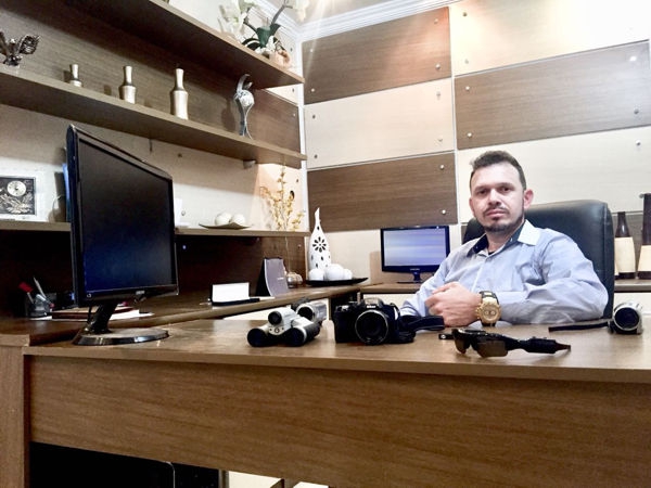 Detetive Particular Alves em seu escritório em Curitiba, com câmeras e equipamentos de investigação sobre a mesa